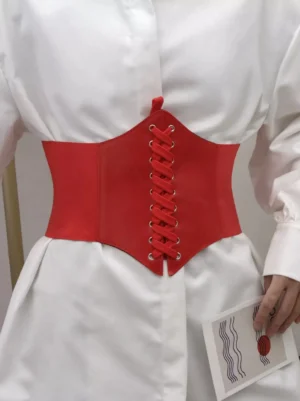 Red vintage corset waist belt with crisscross lacing and elastic side panels on model wearing white shirt fitted waist detail