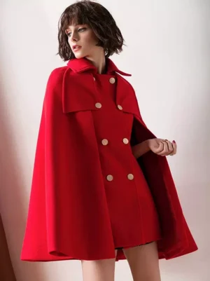 Bright red wool cape poncho with oversized silhouette and double row of gold buttons, three-quarter angle showcasing handkerchief hem and draping flow