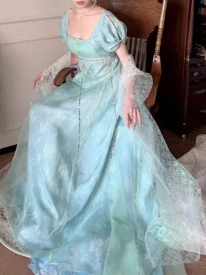 Mint green Regency empire gown with sheer tulle overlay and floor-length skirt, seated side profile view showing elegant drape and silhouette