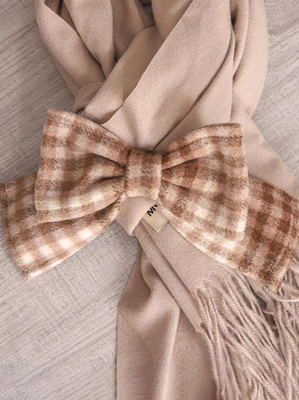 Flat lay top view of brown plaid bow tassel scarf lolita accessory on wooden table background with fringed decoration