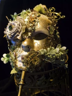 rococo baroque gold floral masquerade handheld mask with silver roses and green leaves on vintage birdcage display