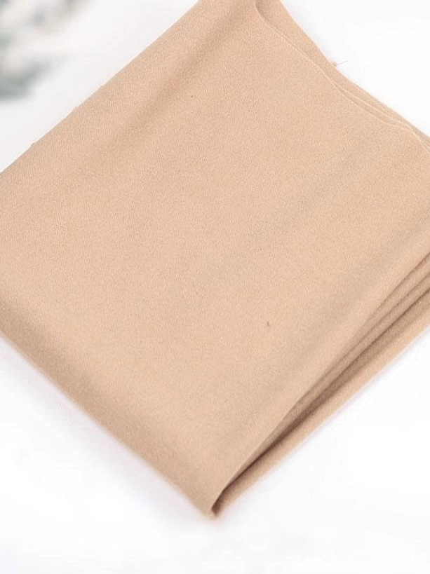 Flat lay side view of light tan brown folded soft lolita scarf accessory showing neat folded edges and fabric texture