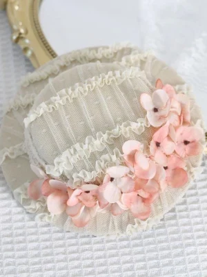 Top-down flat lay of beige mesh Lolita headdress with pink gradient hydrangea wreath and ruffled lace edging on gold mirror tray