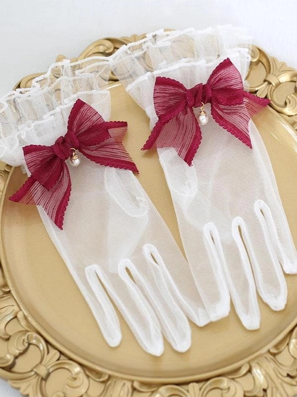 Wine red burgundy pearl bow sheer lolita gloves with ruffled cuffs on ornate gold tray display