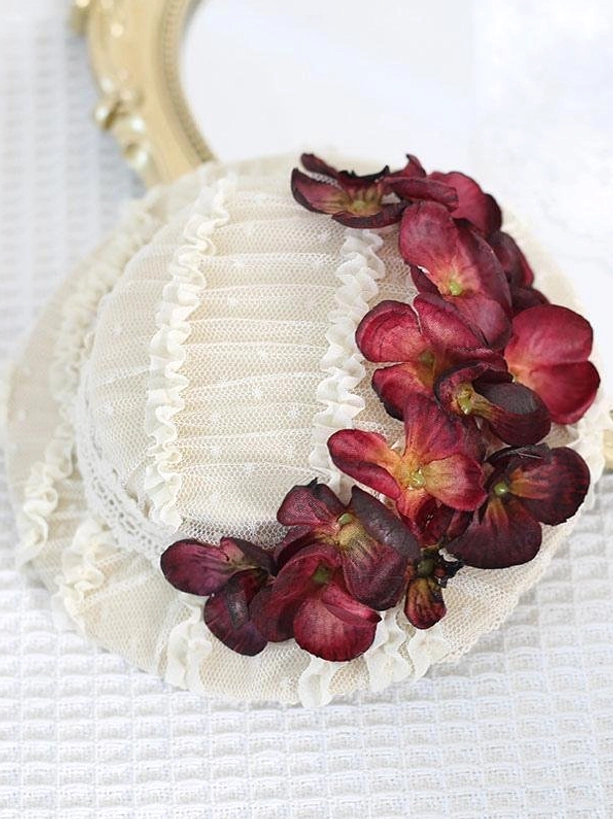 Overhead view of dark red floral Lolita hair hat with cream beige base, wine red hydrangea decoration, and pleated mesh with lace trim