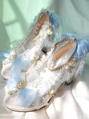 Side top view of ornate lolita pumps showcasing intricate blue bow designs, delicate lace trims, lustrous pearl accents on white leather upper with sturdy heel
