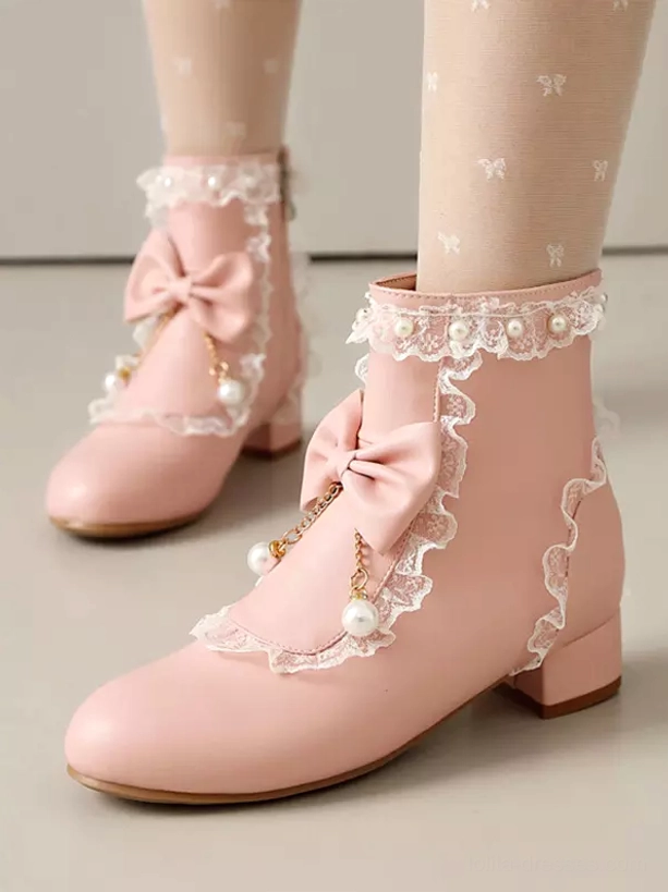 Close-up side view of pink rococo lolita boots highlighting prominent decorative bow, pearl tassel charm accessories and precise lace edge trim construction