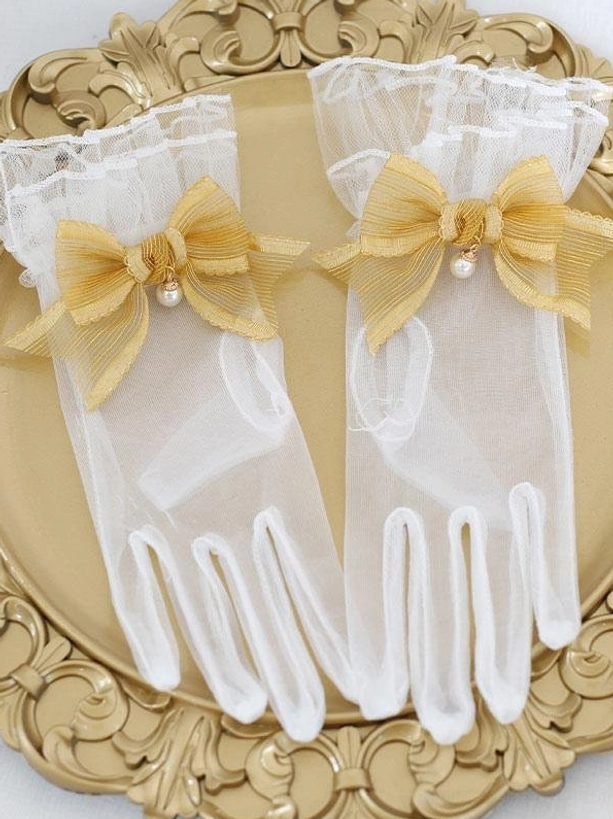 Golden yellow pearl bow sheer mesh lolita gloves with ruffled cuffs on ornate gold tray flat lay