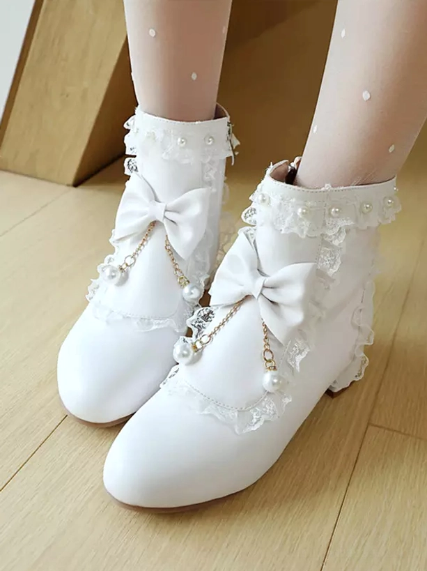 White rococo lolita ankle boots with pearl pendant charms and lace ruffles, front overhead view showing detailed bow ornaments and round toe silhouette with polka dot stockings