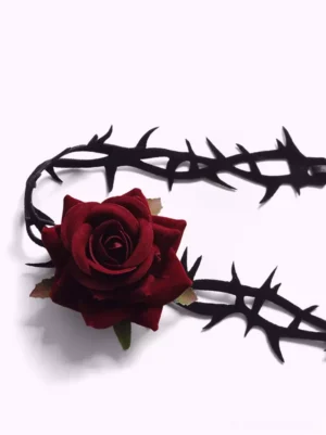 Rose thorn choker flat lay overhead view, black velvet thorn strap with wine-red flocked rose and green leaf details on white background