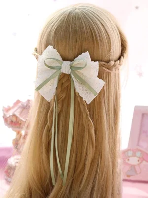 rear view of sage green and off-white lace bow hair clip worn on blonde braided hair, sweet lolita headdress accessory with ribbon streamers