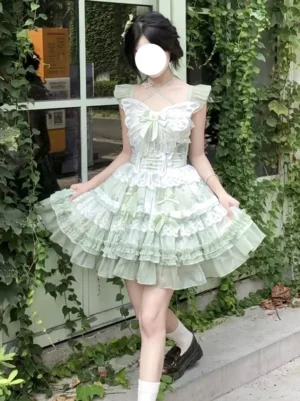 Sage green floral Sweet Lolita JSK dress with butterfly lace chest panel and tiered ruffled skirt, front full-body view showing flutter sleeves and bow accents