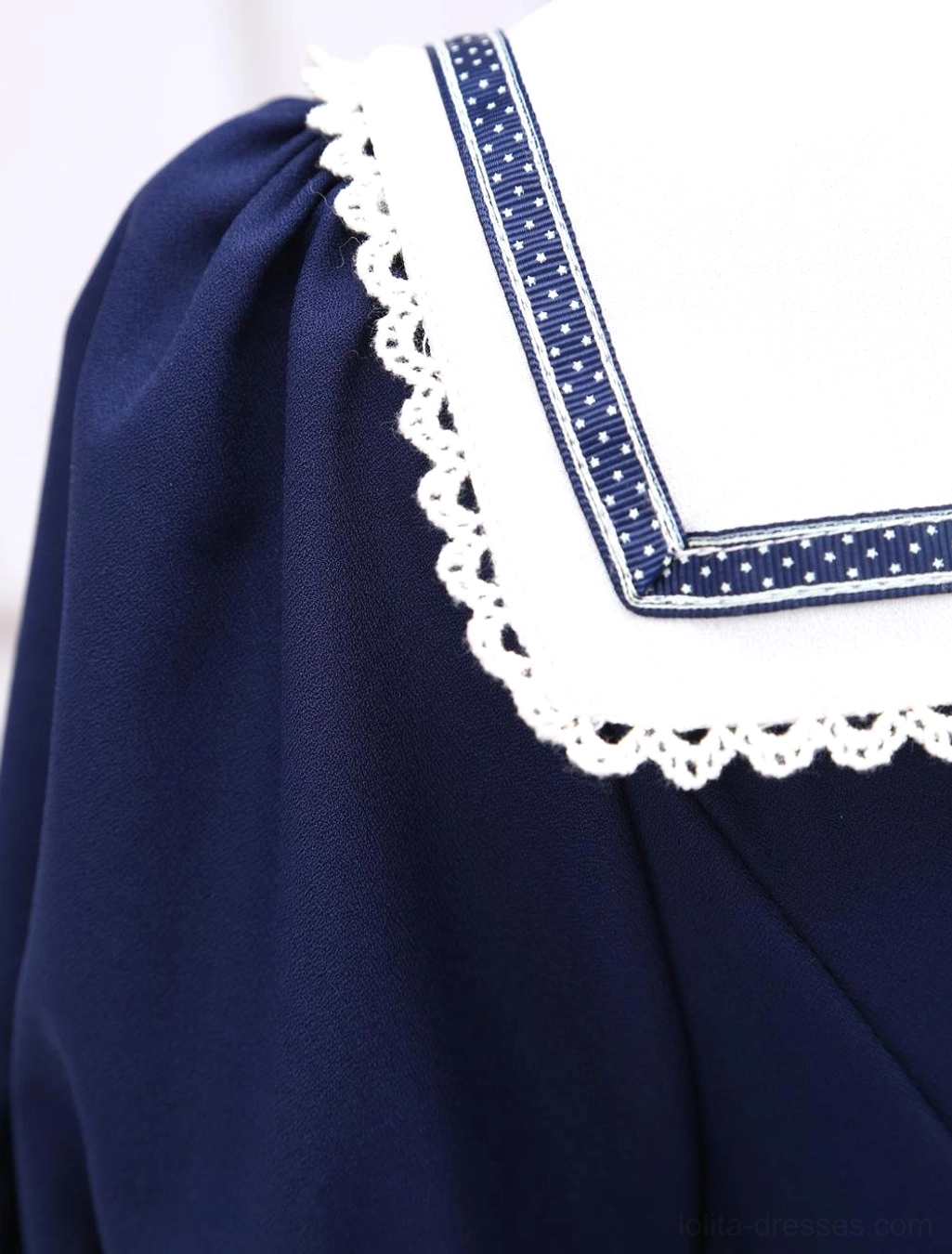 Detailed view of sailor collar with white base, blue polka-dot trim and white ruffled lace border