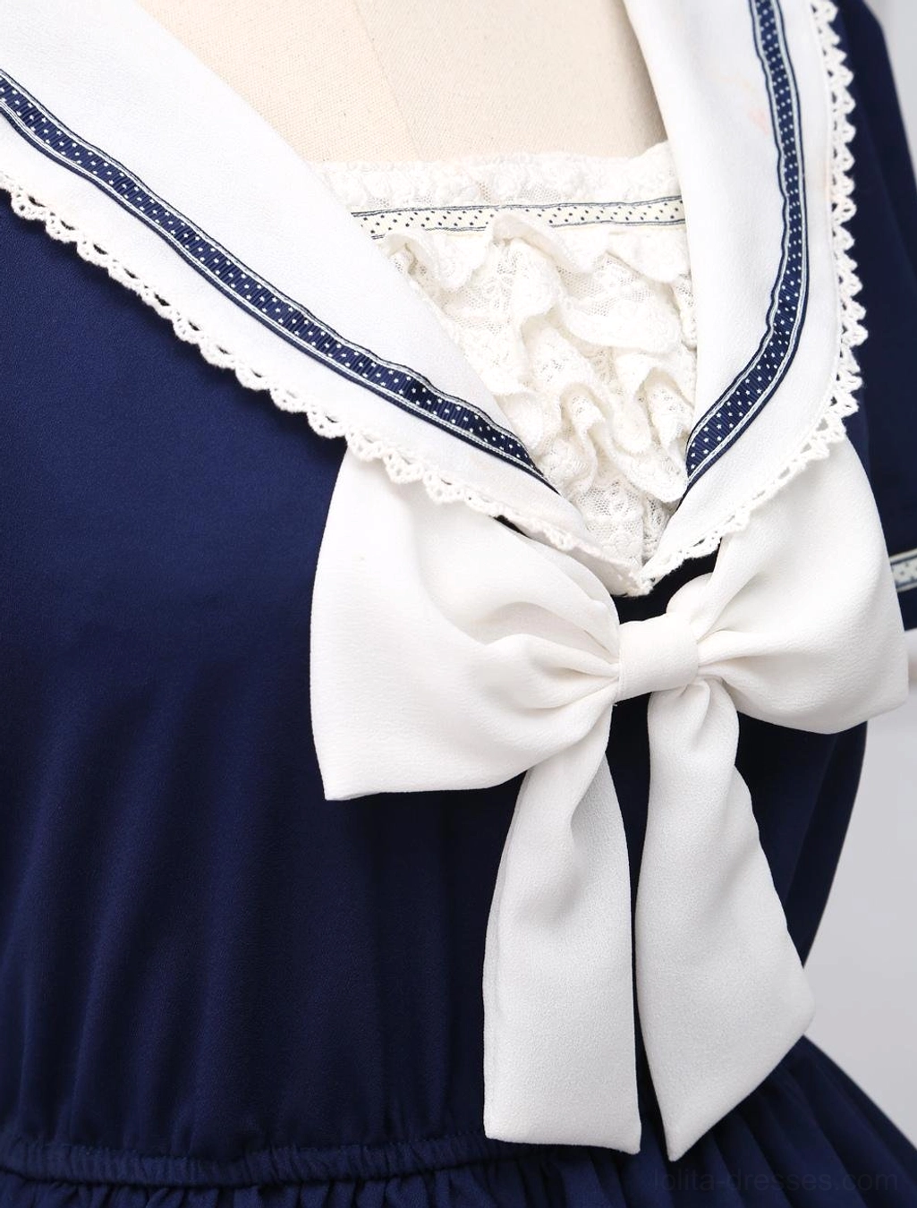 Close-up of sailor collar neckline, white sailor collar with blue trim and ruffled lace, large front bow