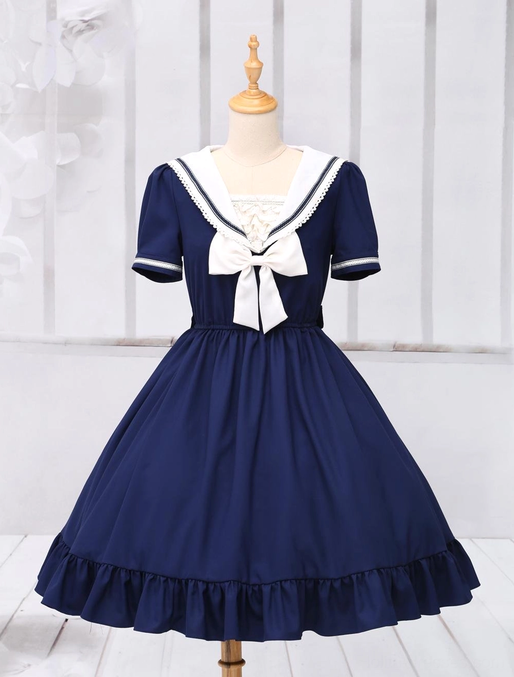 Sailor-style lolita OP dress displayed on dress form, front full view with white sailor collar and large front bow