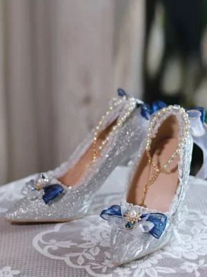 Silver Sweet Bridal Lolita Pumps front three-quarter view with blue bow decorations and glitter upper on lace tablecloth backdrop