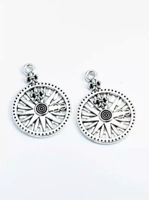 Silver-toned compass metal pendants flat lay front view, engraved compass design with dotted edge detailing, attached jump rings, gothic lolita accessory on white background, jewelry photography