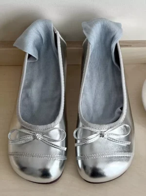 Silver Lolita ballet flats showcase light blue ribbed sock lining, decorative bow embellishment, overhead flat lay photography