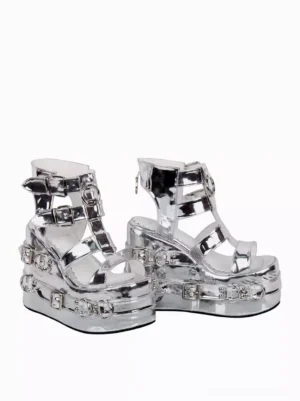 Silver gladiator-style Lolita platform sandals side three-quarter view displaying ankle buckle straps, chunky wedge sole, metal grommet details, and patent silver finish