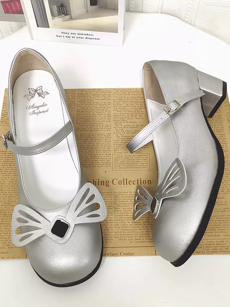 Paired silver Lolita pumps displayed on vintage newspaper background showing brand logo on insole, large hollow bow ornament detail, and overall Sweet Lolita aesthetic
