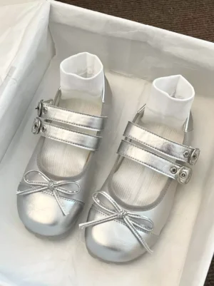 Silver Mary Jane flat Lolita pumps with dual buckle straps and bow ornament displayed in white shoe box flat lay top view