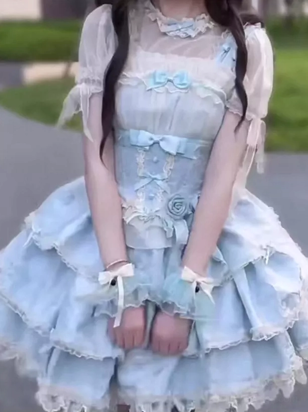 Short-sleeve variation of sky blue sweet lolita dress with sheer sleeves, decorative rose and bow embellishments on bodice, outdoor street scene setting