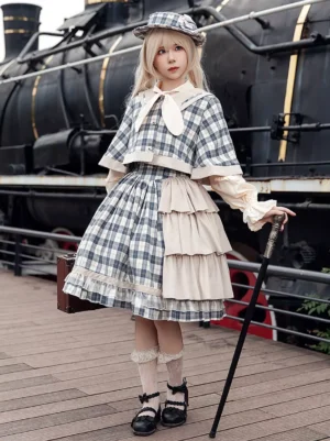 Classic light sky blue plaid lolita poncho with sailor collar and bow details worn as full front coordinate with tiered ruffled skirt and rabbit ear bow tie on blonde model at vintage steam train platform