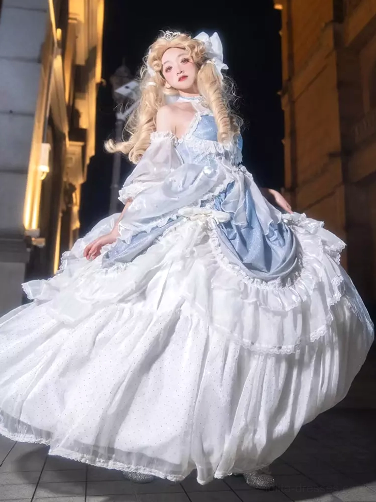 Light sky blue Rococo Lolita ball gown with tiered ruffles, white floral print, puff sleeves, and statement bow details - front three-quarter view