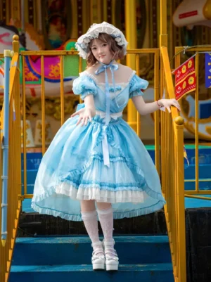 Sky blue sweet lolita dress with off-shoulder puff sleeves and high-low ruffled hem, front three-quarter view showing layered skirt design and satin ribbon accents at amusement park location