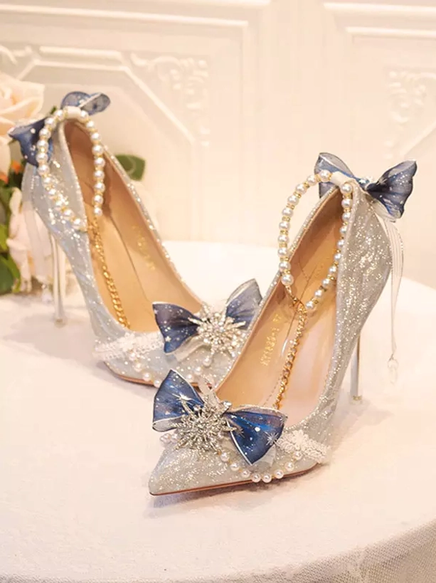 Overhead shot with dark blue tulle bow pearl ankle strap snowflake crystal decor clear stiletto heel on floral backdrop