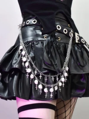 Steampunk gothic waist chain belt worn on model with black top and ruffled leather skirt, featuring black grommet belt with layered silver chains, cross and bead pendants, front lower body view