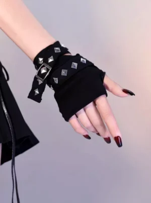 Black steampunk lolita fingerless wrist cuff with silver pyramid studs and adjustable buckle strap, shown on hand with dark red nail polish and partial black leather goth skirt background
