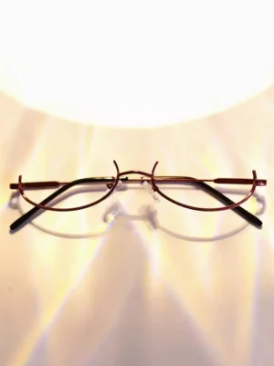 lensless burgundy wine-red metal half-rim glasses frame with black temple arms photographed from positive overhead view under warm lamp lighting showing clear silicone nose pads