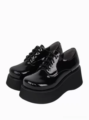 Black patent leather steampunk lolita platform shoes front three-quarter view, displaying round toe, glossy finish, and metal eyelet lace-up system with thick platform sole