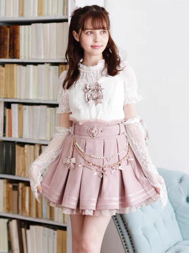Pink steampunk lolita pleated skirt with white grommets and heart belt buckle, front full-body view with pearl chain accessories and ruffled lace hem