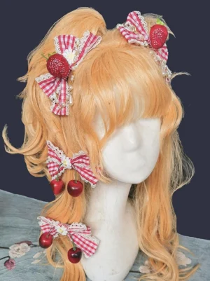 Strawberry cherry gingham Lolita hair bow with pearl accents displayed on blonde curly wig mannequin three-quarter front view showing fruit charm details and lace edging