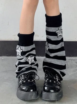 Close-up front view of black-grey striped knit leg warmers with star appliqués and ribbed cuff detail on model wearing platform boots