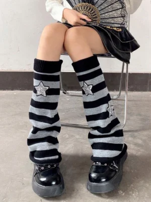 Black-grey striped leg warmers with glitter star patches worn with mini skirt and platform loafers - front seated view of sweet lolita socks