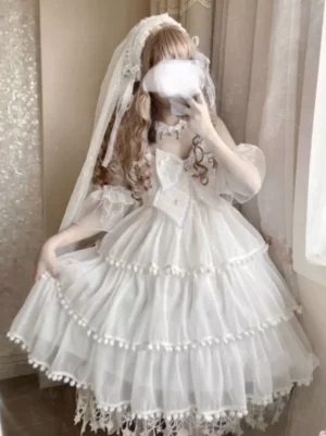 White tiered ice cream fairy Lolita JSK dress with pearl bows, pom poms and tulle skirt worn with bridal veil, three-quarter front view