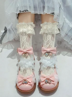 Pink sweet Lolita ankle strap heels with bow embellishments and gem pendants worn with lace ruffled socks and white tulle skirt front view