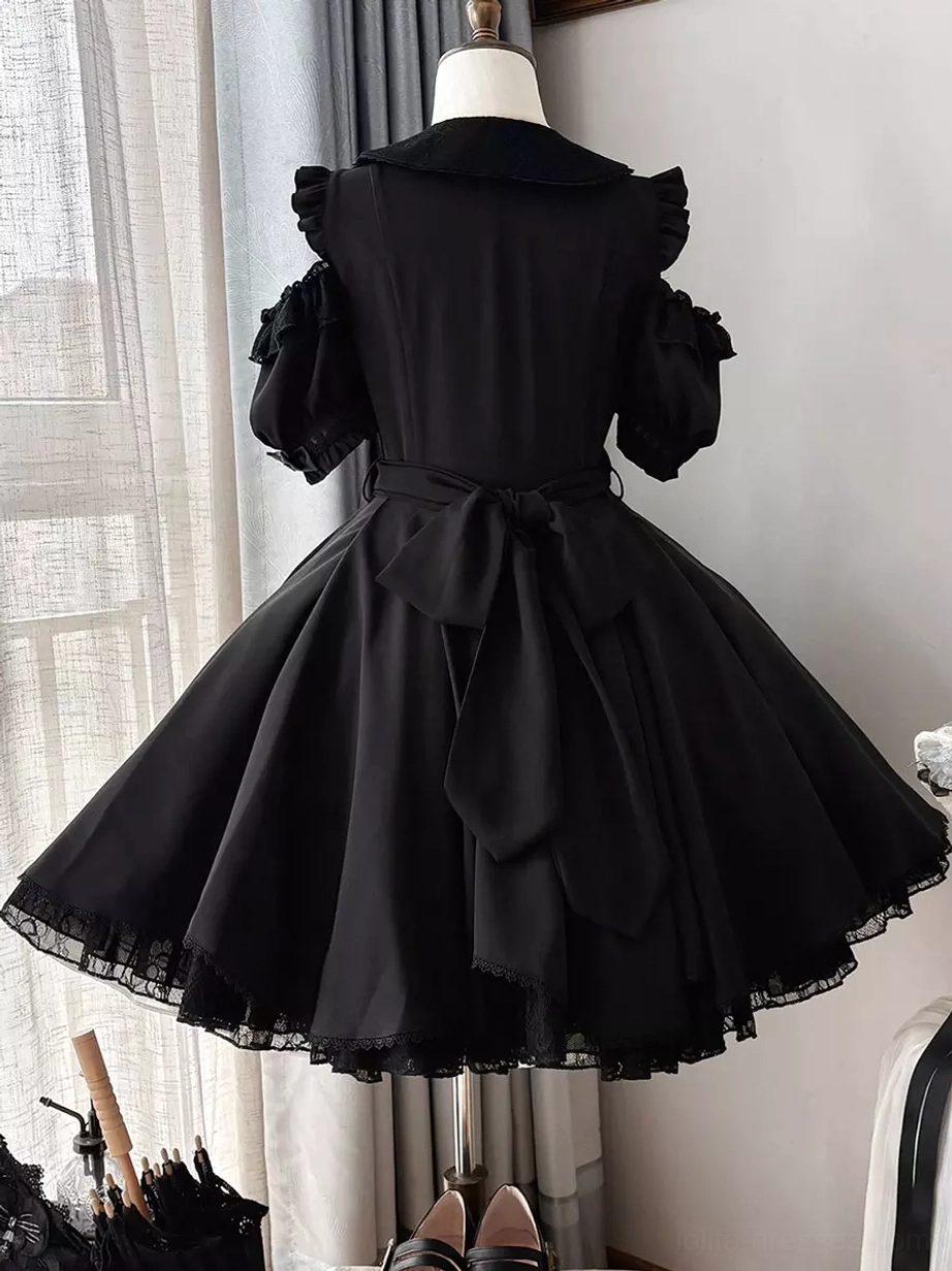Black sweet lolita mini dress back view on dress form showing large back waist bow pleated skirt lace-trimmed hem window background detail