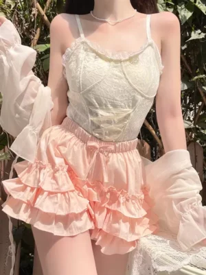 Styled sweet lolita coordinate featuring pink ruffled bloomers with lace camisole sheer cardigan and pearl necklace outdoor look