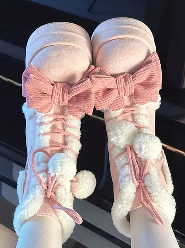 Paired pink lolita platform ankle boots on model feet flat lay top-down view corduroy bows fuzzy pom poms lace-up design