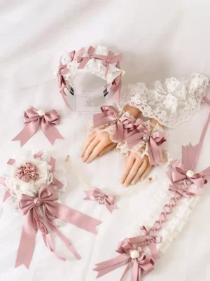 Complete Sweet Lolita oversleeves accessory set flat lay featuring dusty pink satin bows off-white ruffled lace pearl gem embellishments and three-dimensional floral decorations on white background