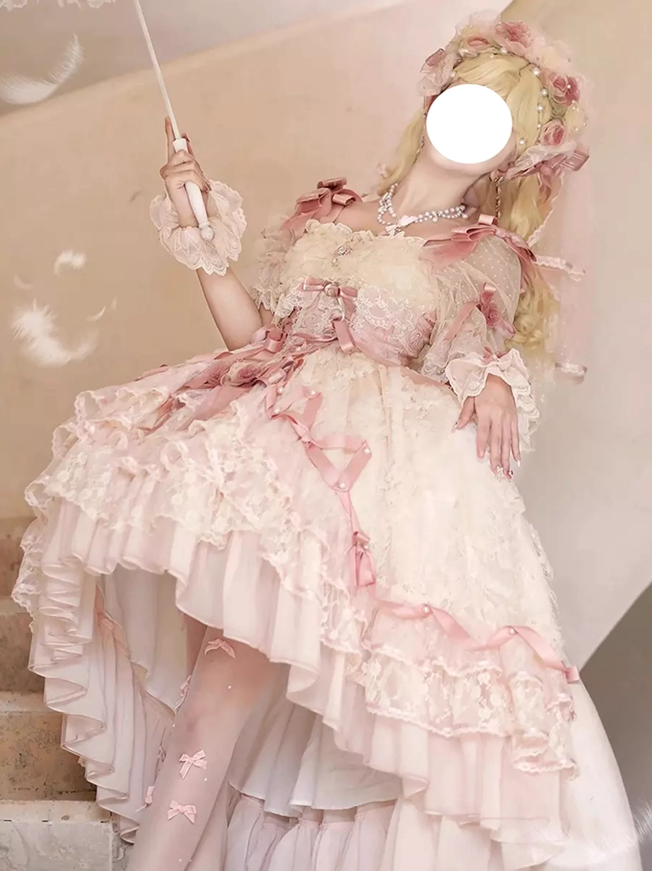 Low-angle frontal view of sweet lolita bridal dress worn by blonde model with flower headdress asymmetrical high-low hem pink ribbon trims