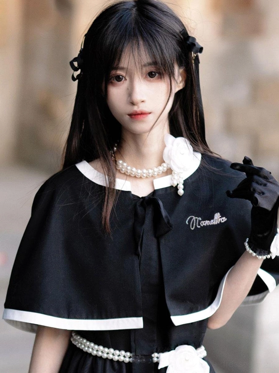 Lolita dress with matching capelet close-up front upper shot showing embroidered text white trim detail and pearl flower necklace