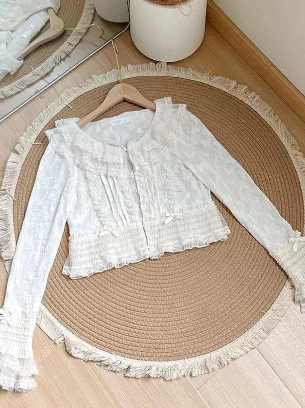 Ecru white lace ruffle lolita cardigan with square collar and puff sleeves flat lay overhead view showing intricate lace details and ruffled cuffs on wooden floor