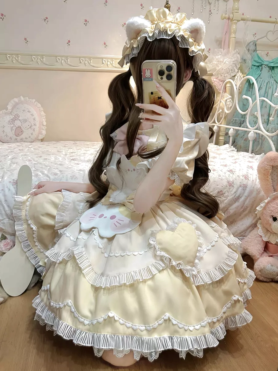 Beige and white sweet lolita cat dress front sitting perspective with ruffled hem, plush heart decoration, cat face patch, model wearing crown bear ear accessories