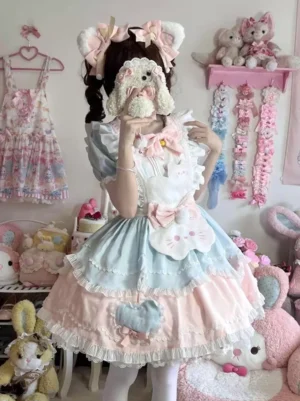 Pink and blue pastel sweet lolita cat dress front perspective showing layered ruffles and bow embellishment, model with plush dog prop in lolita bedroom aesthetic