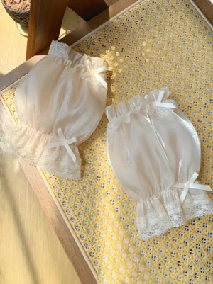Sweet Lolita champagne puff oversleeves with delicate lace trims and white satin bows, displayed on wooden table with yellow placemat
